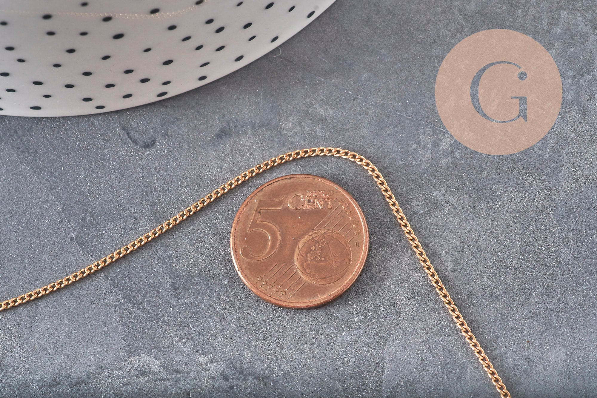 Chaîne plate en laiton brut de 1,5 mm pour bijoux DIY, présentée sur un fond gris avec une pièce de 5 centimes.