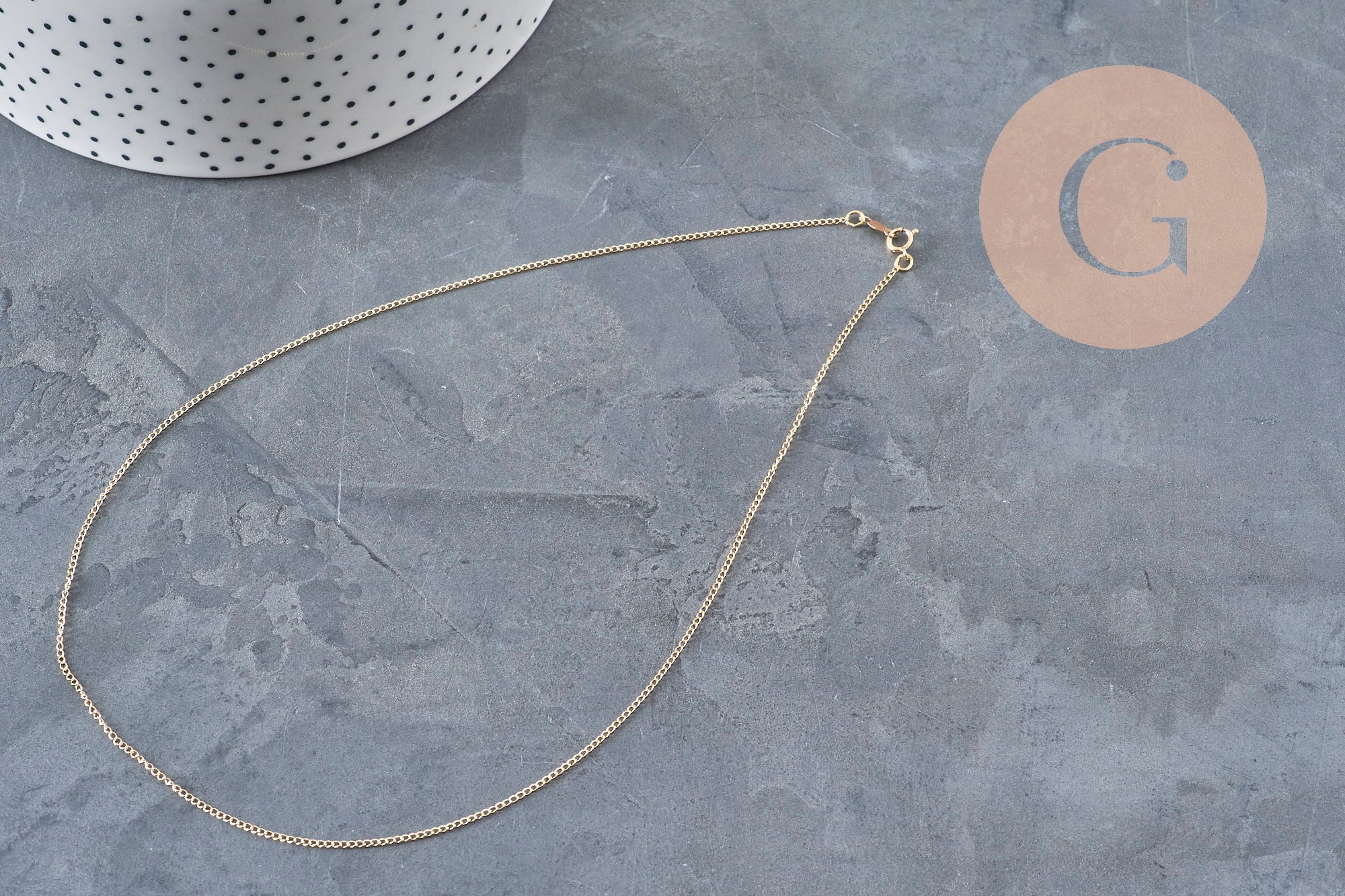 Collier chaîne fine gold-filled 14K dorée de 45.7cm avec fermoir, sur fond gris.