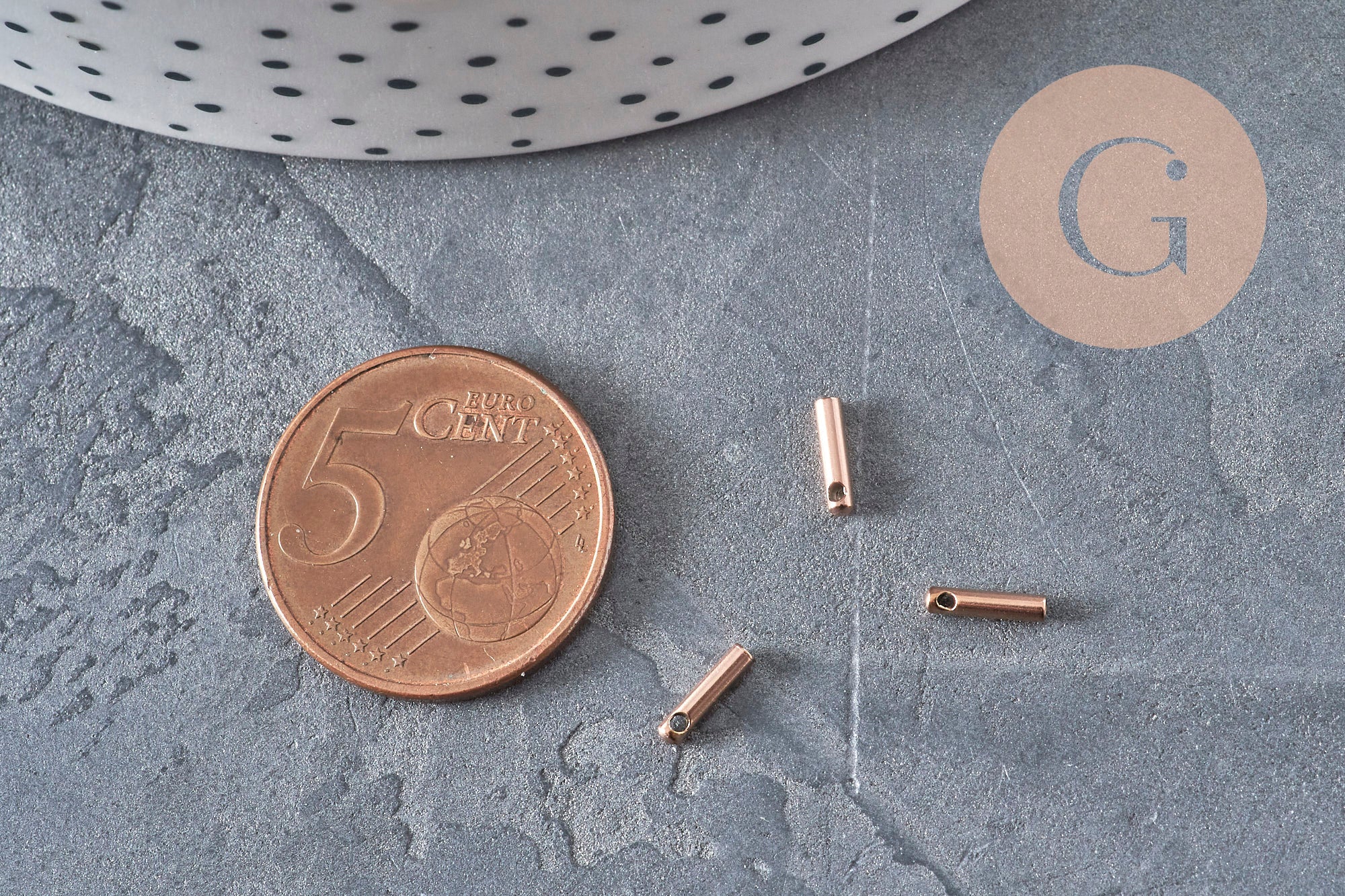 Embouts de cordon cylindriques en acier inoxydable or rose 7x1,6mm, présentés à côté d'une pièce de 5 centimes.