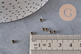 Perles à écraser rondelles en laiton couleur bronze 3x2mm, présentées avec une règle.