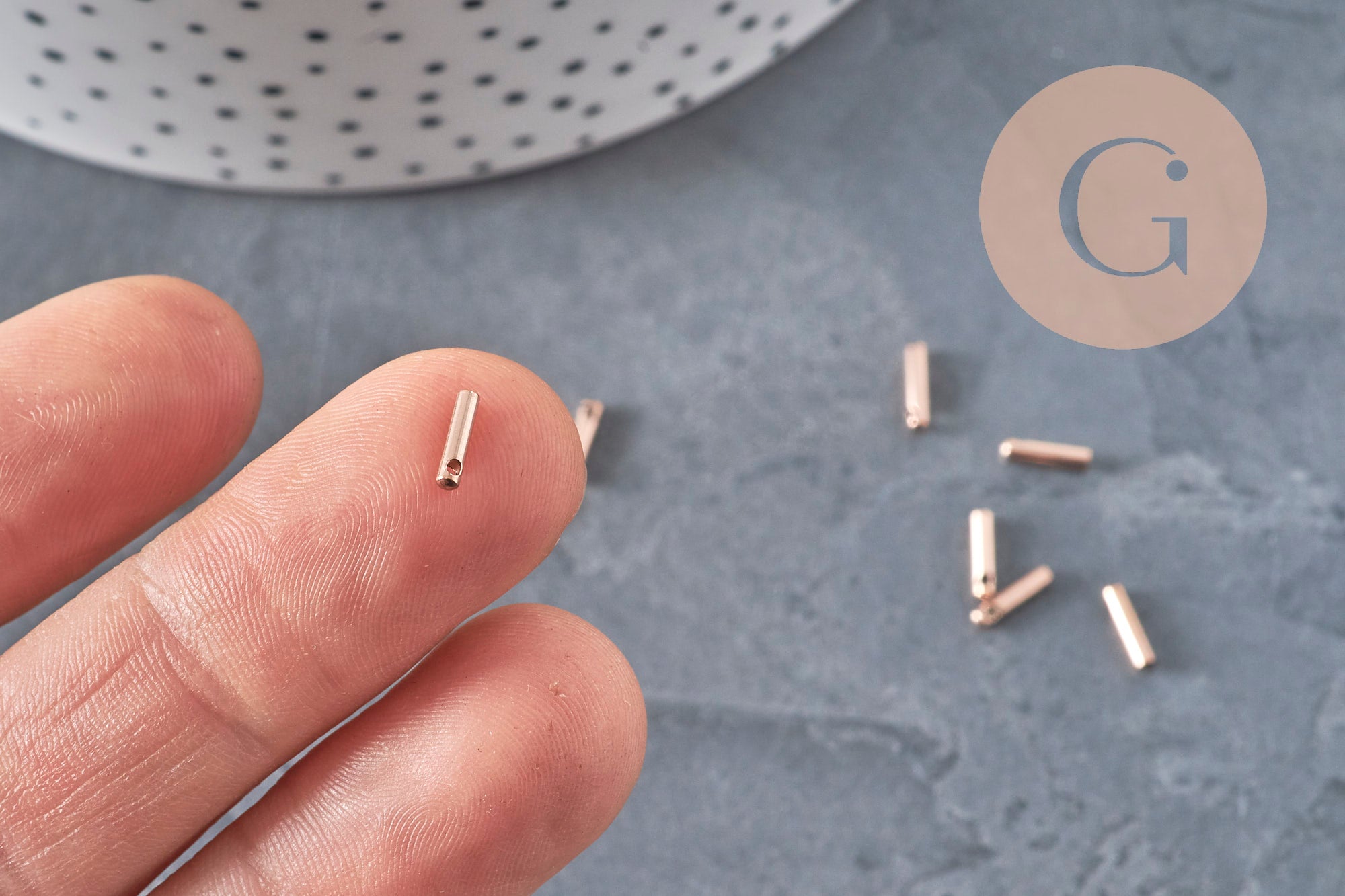 Embouts de cordon cylindriques en acier inoxydable or rose 7x1.6mm pour bijoux DIY, tenus sur le bout d'un doigt.