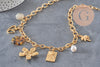 Collier DIY en chaîne dorée acier inoxydable 304 avec breloques cœur, fleur, perles nacrées et médaillons sur fond gris.