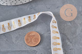 Ruban élastique blanc de 16mm avec motifs ananas dorés pour créations DIY, posé sur un fond gris texturé.